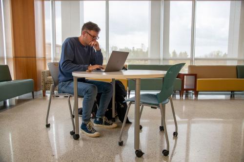 Student studying at table with laptop