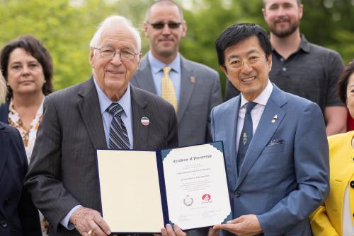 Two men posing with signed agreement.