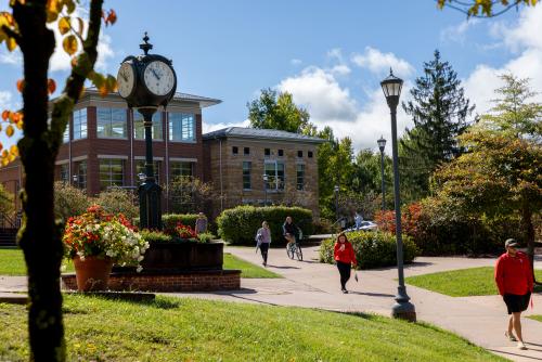 Campus clock with students walking on sidewalk