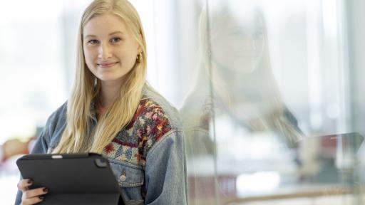 Girl standing against wall holding iPad