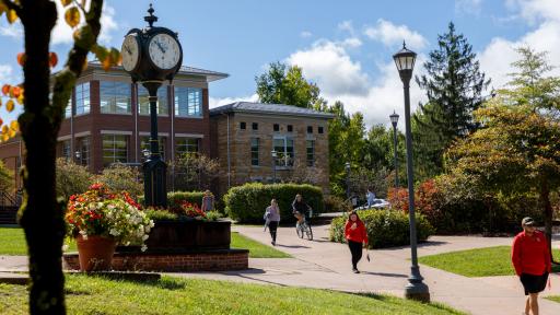 Campus clock with students walking on sidewalk